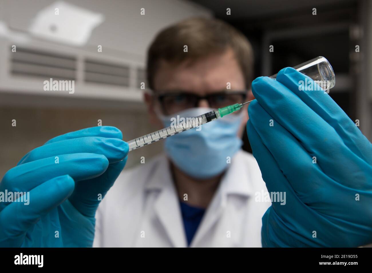 Vaccin contre le coronavirus prêt pour l'immunisation. Médecin avec des mains gantées tenant une aiguille hyperdermique et dose de vaccination Banque D'Images