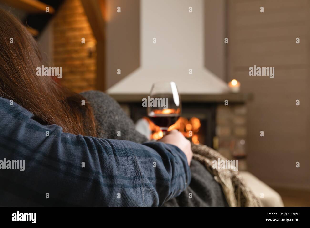 Couple amoureux assis dans une chambre confortable avec cheminée sur un canapé avec un verre de vin. Concept de famille et d'amour. Banque D'Images