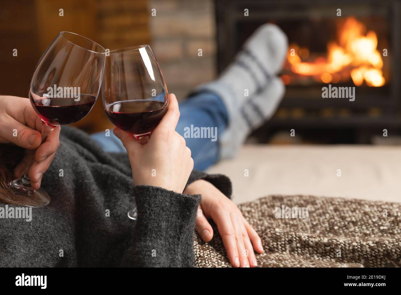 Couple amoureux assis dans une chambre confortable avec cheminée sur un  canapé avec un verre de vin. Concept de famille et d'amour Photo Stock -  Alamy