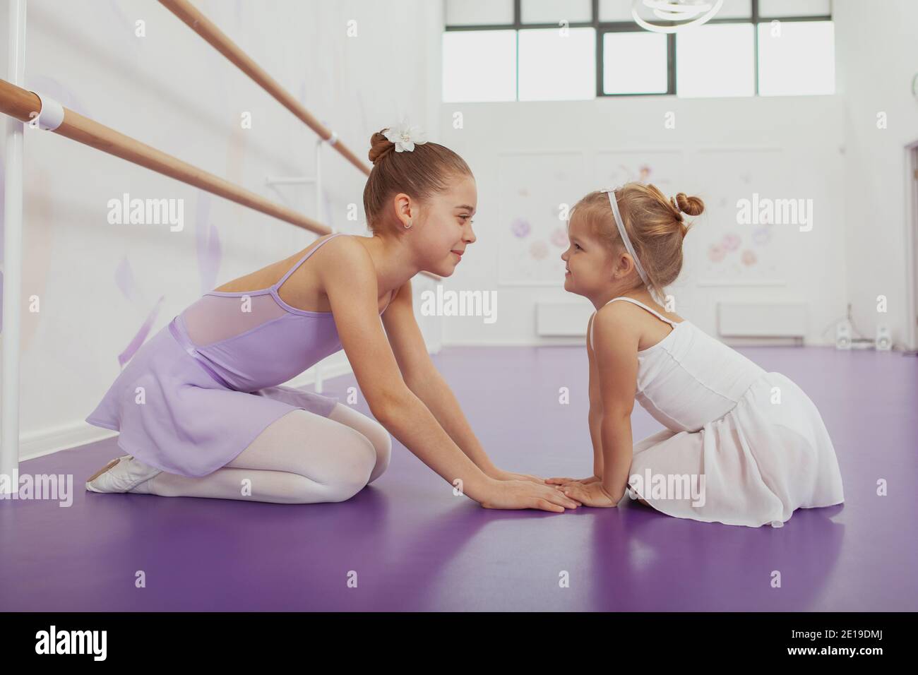Deux adorables filles ballerines assis face à face, tenant les mains,  souriant l'une à l'autre à l'école de ballet. Belle ballerine jeune et sa  jolie litt Photo Stock - Alamy