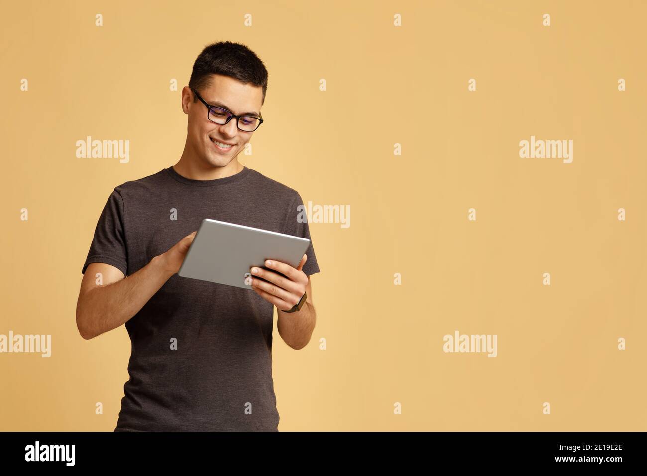 Travailler en ligne, freelance, professeur et blogueur. Un jeune homme souriant et mignon se présente sous forme de tablette Banque D'Images