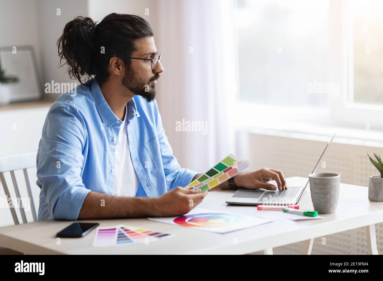 Jeune homme concepteur indépendant de l'est travaillant avec l'ordinateur portable et la couleur Nuances Banque D'Images