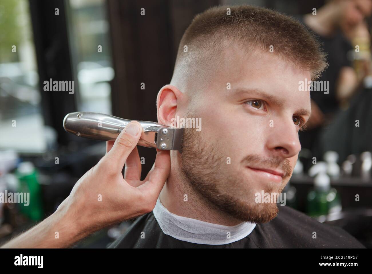 Gros plan sur un homme charmant souriant en train d'obtenir sa barbe taillée par barber Banque D'Images