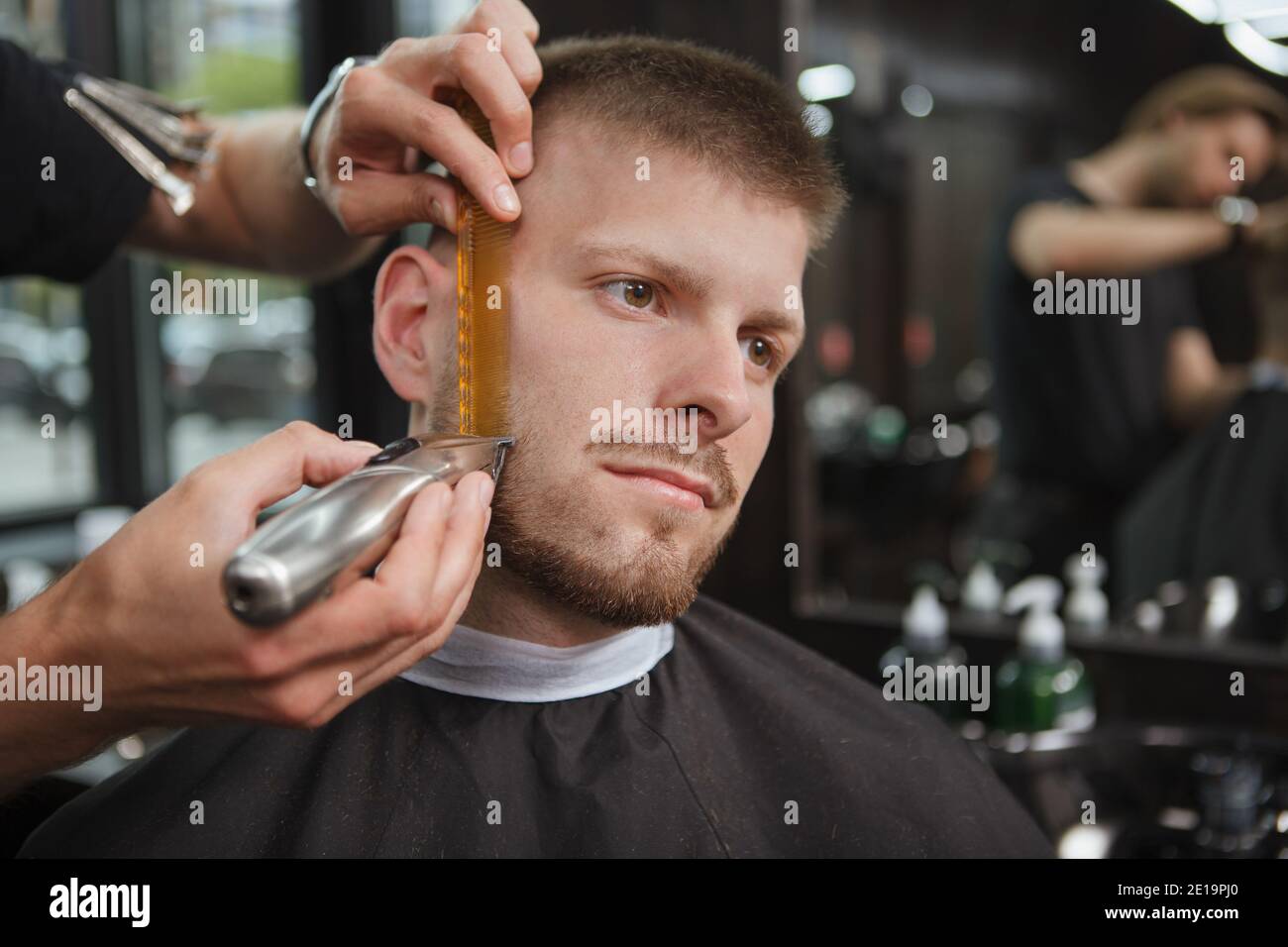 Client masculin au salon de coiffure, qui a taillé la barbe par un barbier professionnel Banque D'Images