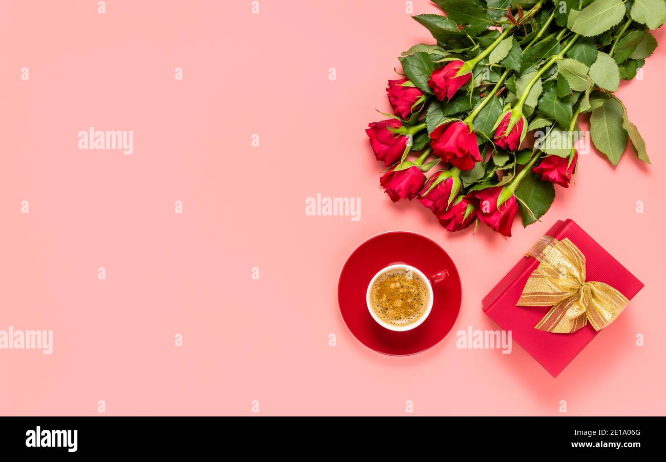 Bouquet de roses rouges, boîte-cadeau avec noeud doré et tasse de café sur fond rose. Anniversaire, fête des mères, des femmes ou de la Saint-Valentin. Amour Banque D'Images