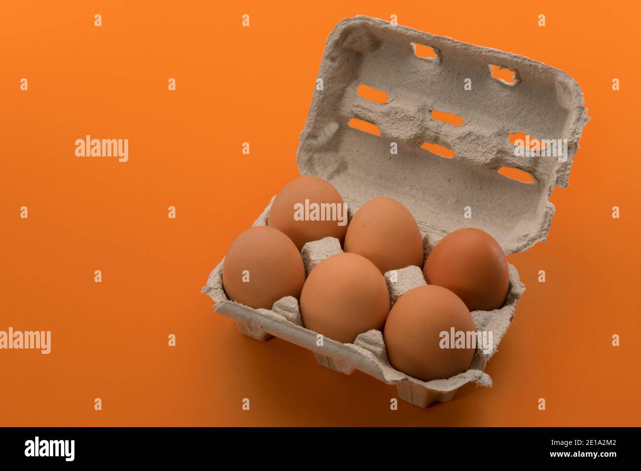 Boîte à œufs avec œufs, six œufs de poulet dans un plateau à œufs en carton fabriqué à partir de papier recyclé isolé sur fond orange Banque D'Images