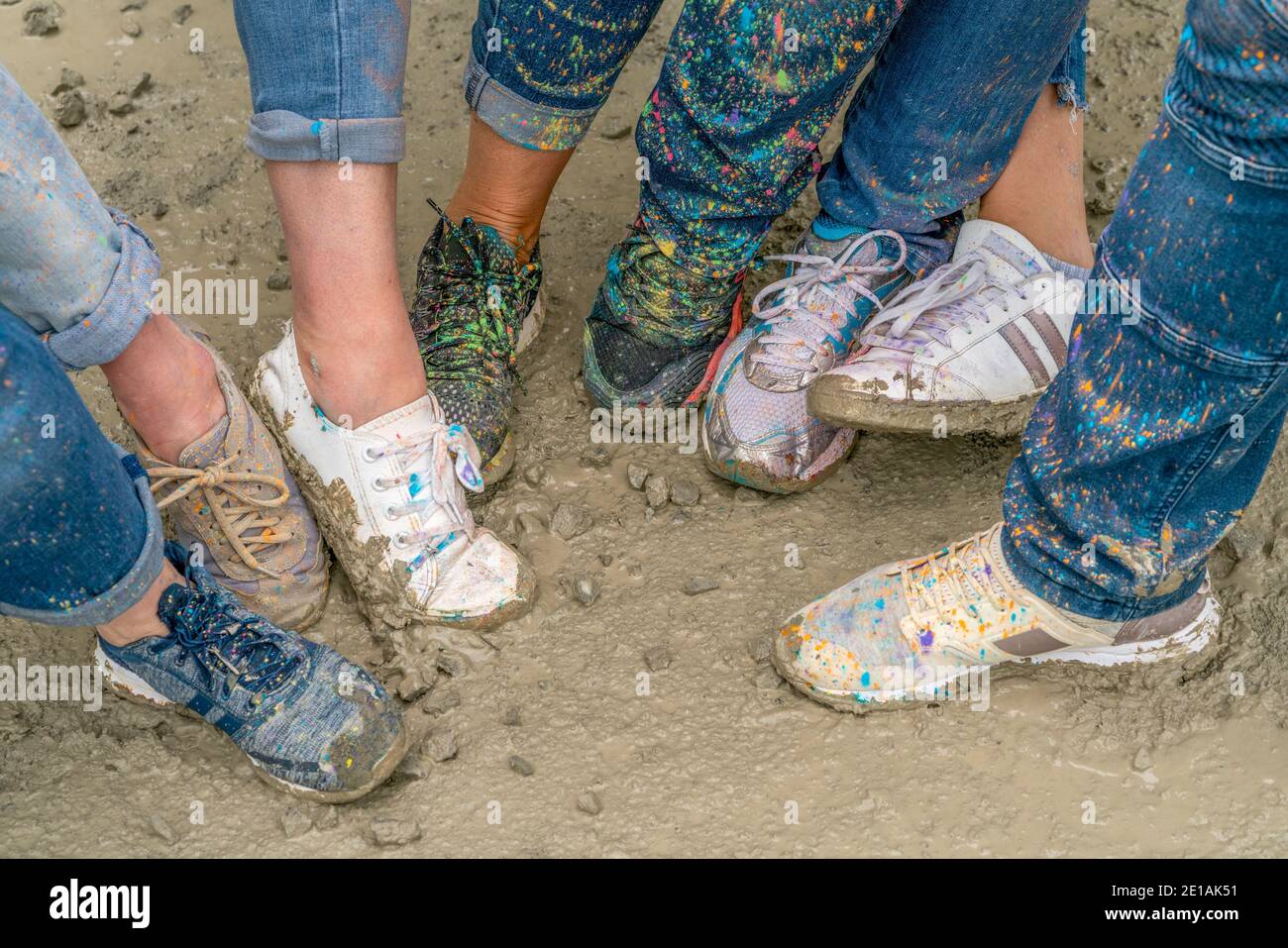 chaussures tachetées avec des taches de peinture colorées sur sol boueux Banque D'Images