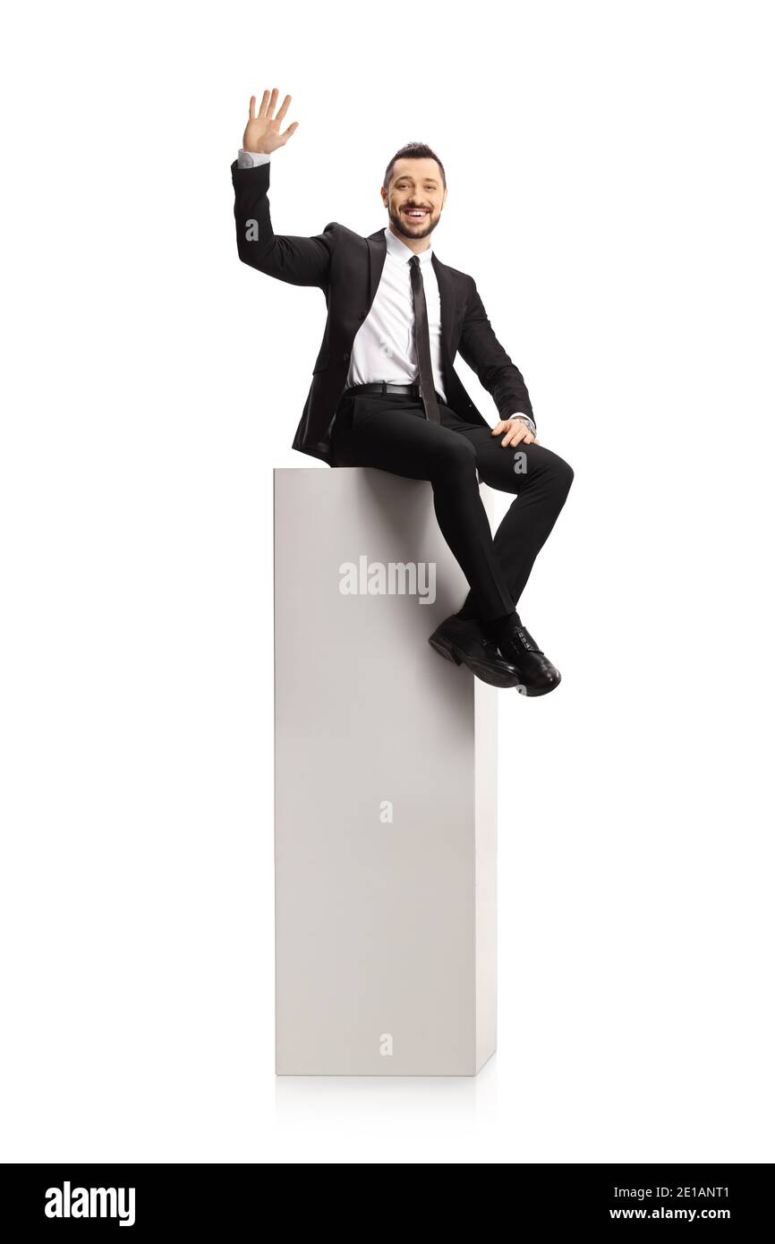 Homme d'affaires assis sur une grande colonne blanche et agitant à caméra isolée sur fond blanc Banque D'Images