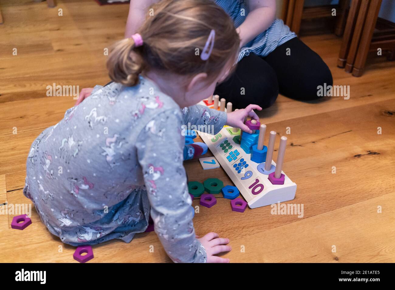 Une fille apprenant à compter avec sa mère en utilisant un jouet éducatif. Apprenant par essai et par erreur, elle a placé une forme colorée dans le mauvais domaine Banque D'Images