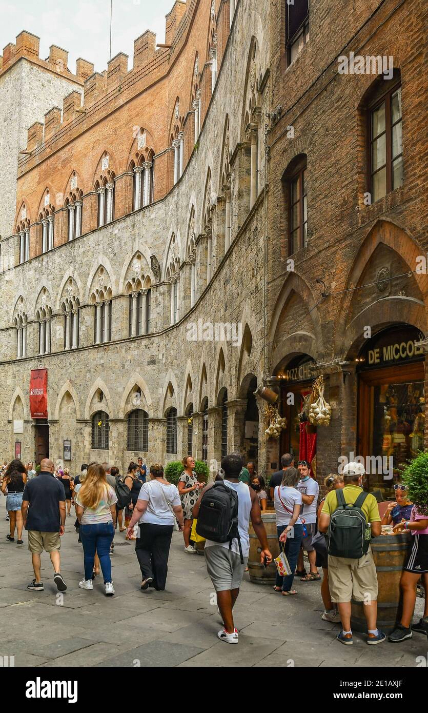 Personnes et touristes devant le palais médiéval de Palazzo Chigi-Saracini, dans le centre historique de Sienne (site classé au patrimoine mondial de l'UNESCO), Toscane, Italie Banque D'Images
