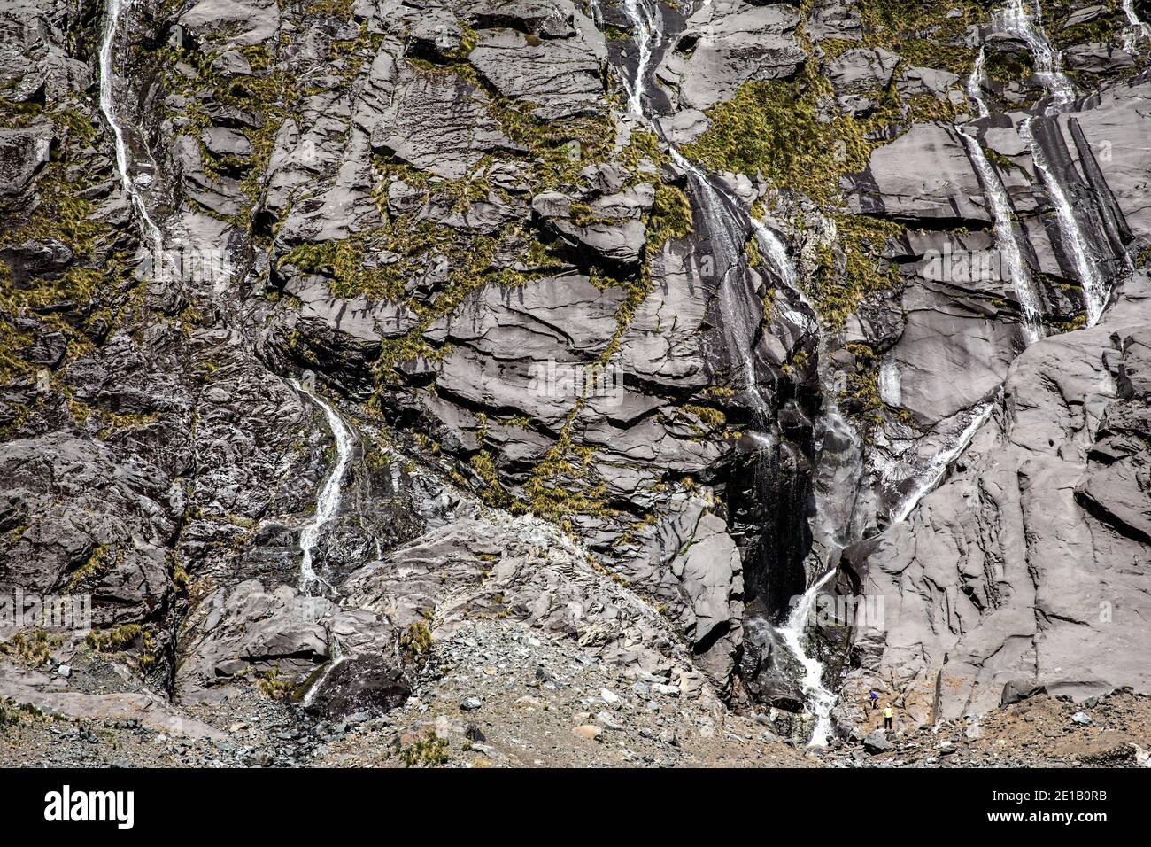 Les randonneurs admirent plusieurs cascades sur une falaise sur la route de Milford Sound, South Island, Nouvelle-Zélande Banque D'Images
