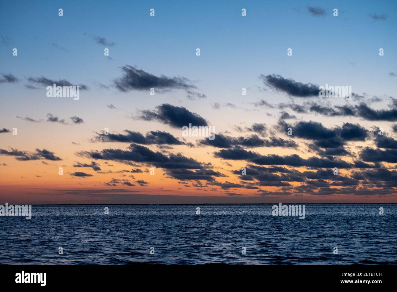 Vue sur le soleil couchant qui brille sur la mer et se reflète sur la plage, nuages avec des bords ensoleillés. Paysage. Photo de haute qualité montrant le concept de liberté et de rêves Banque D'Images