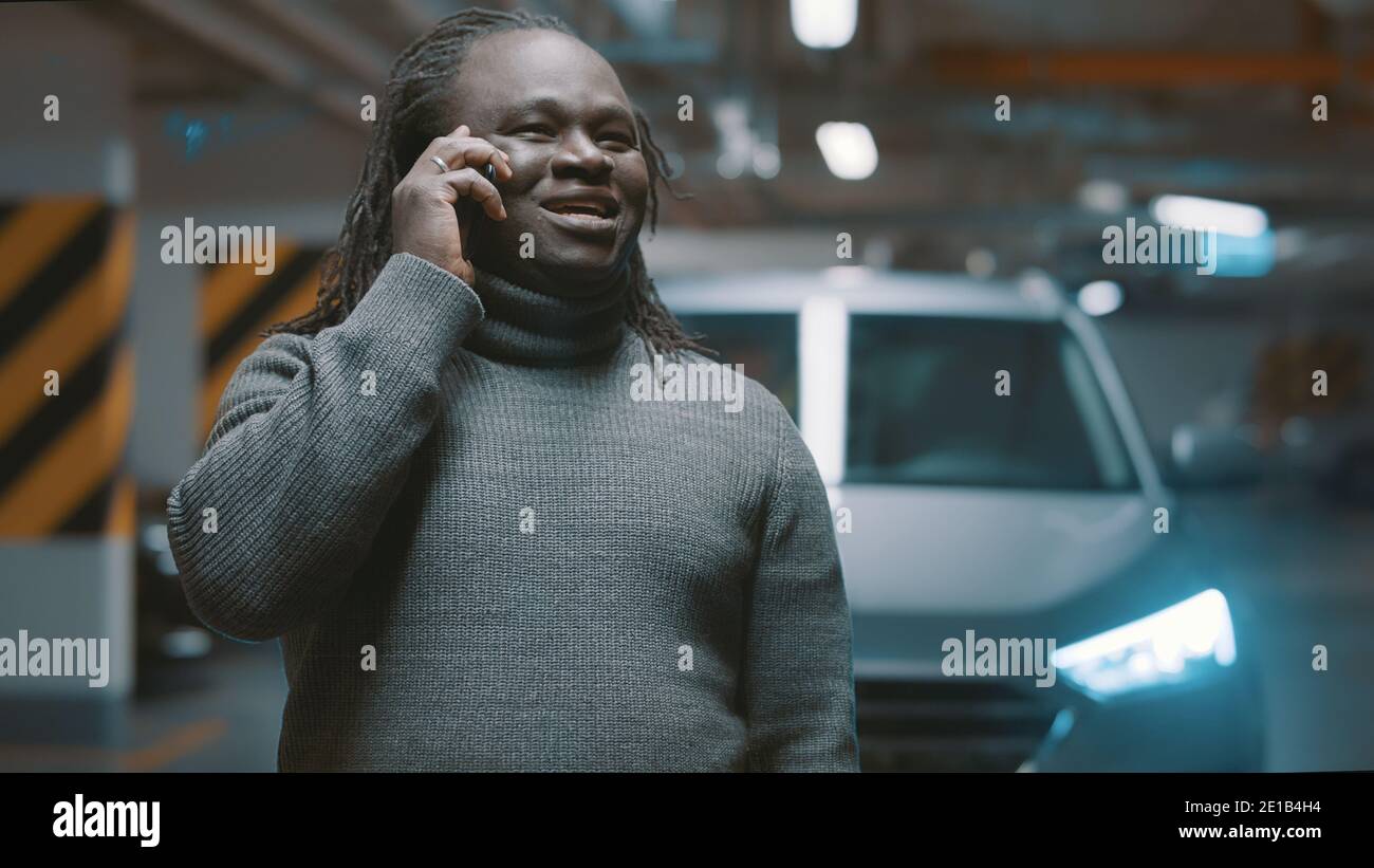 Un homme noir afro-américain enthousiaste qui a eu une conversation téléphonique dans le parking souterrain. Photo de haute qualité Banque D'Images