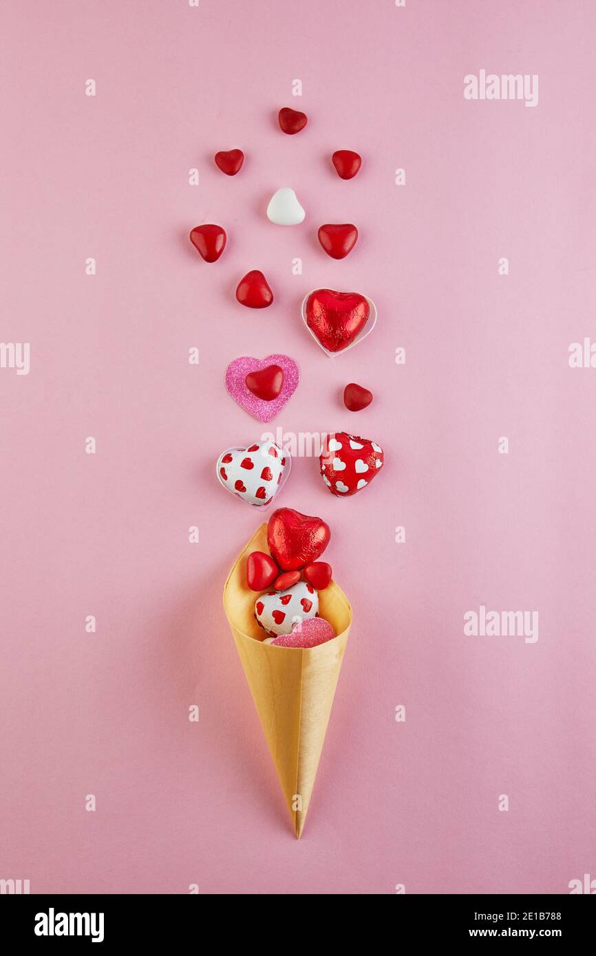 Carte de Saint-Valentin avec coeurs en sucre volant d'un cône de glace sur fond rose. Vue de dessus avec un endroit pour vos salutations Banque D'Images