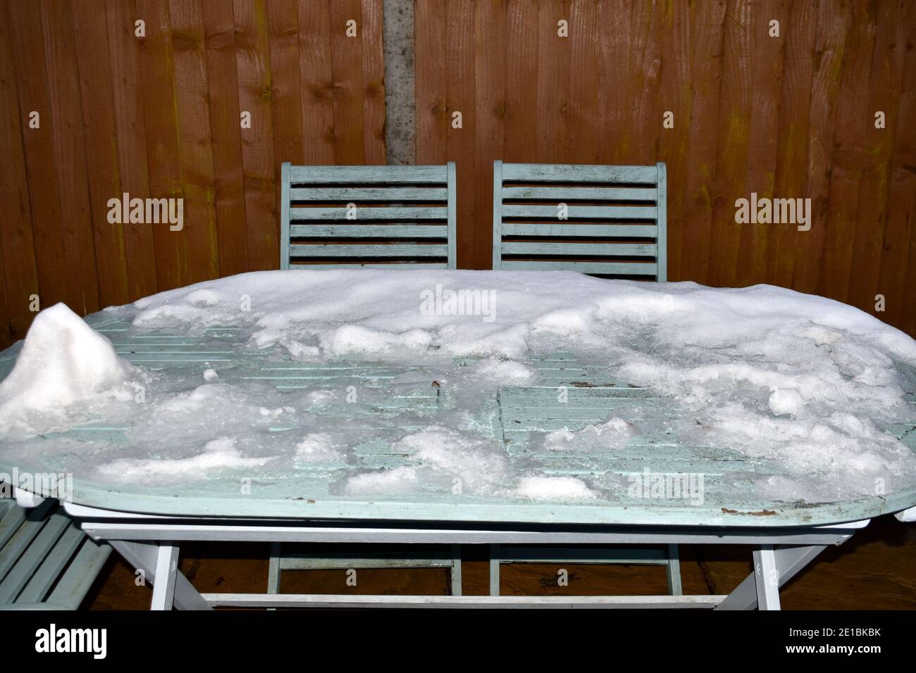 gros plan sur l'image en noir et blanc de la neige recouverte table de jardin rustique avec chaises vides à l'extérieur en hiver Banque D'Images