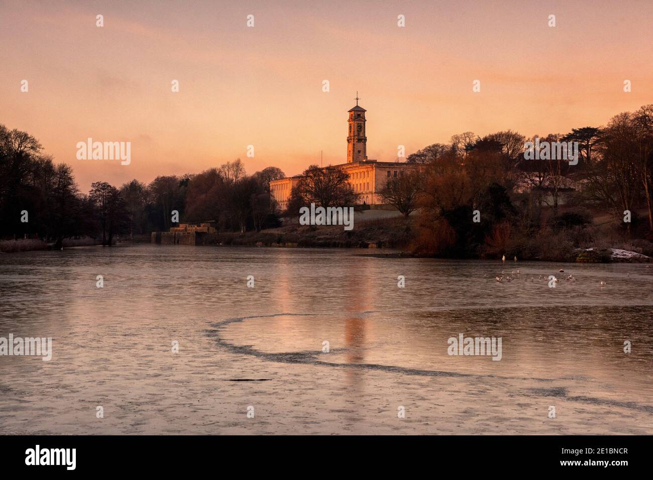 Lever du soleil tôt le matin lumière au-dessus d'un lac gelé à Highfields University Park, Nottingham Notinghamshire Angleterre Royaume-Uni Banque D'Images