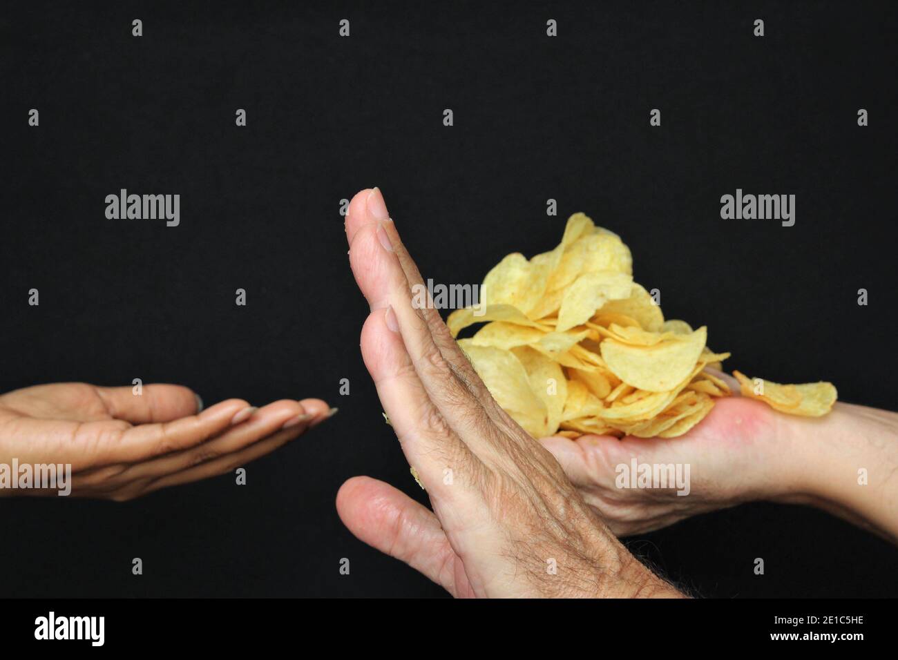 Flou femme main demandant des chips de pomme de terre des mains de l'homme miser. Photo de stock sur fond noir espace de copie Banque D'Images