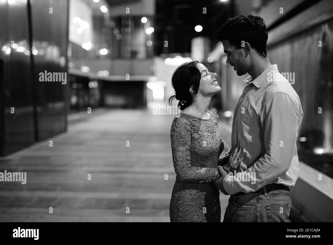 Jeune couple hispanique explorant les rues de la ville la nuit ensemble Banque D'Images