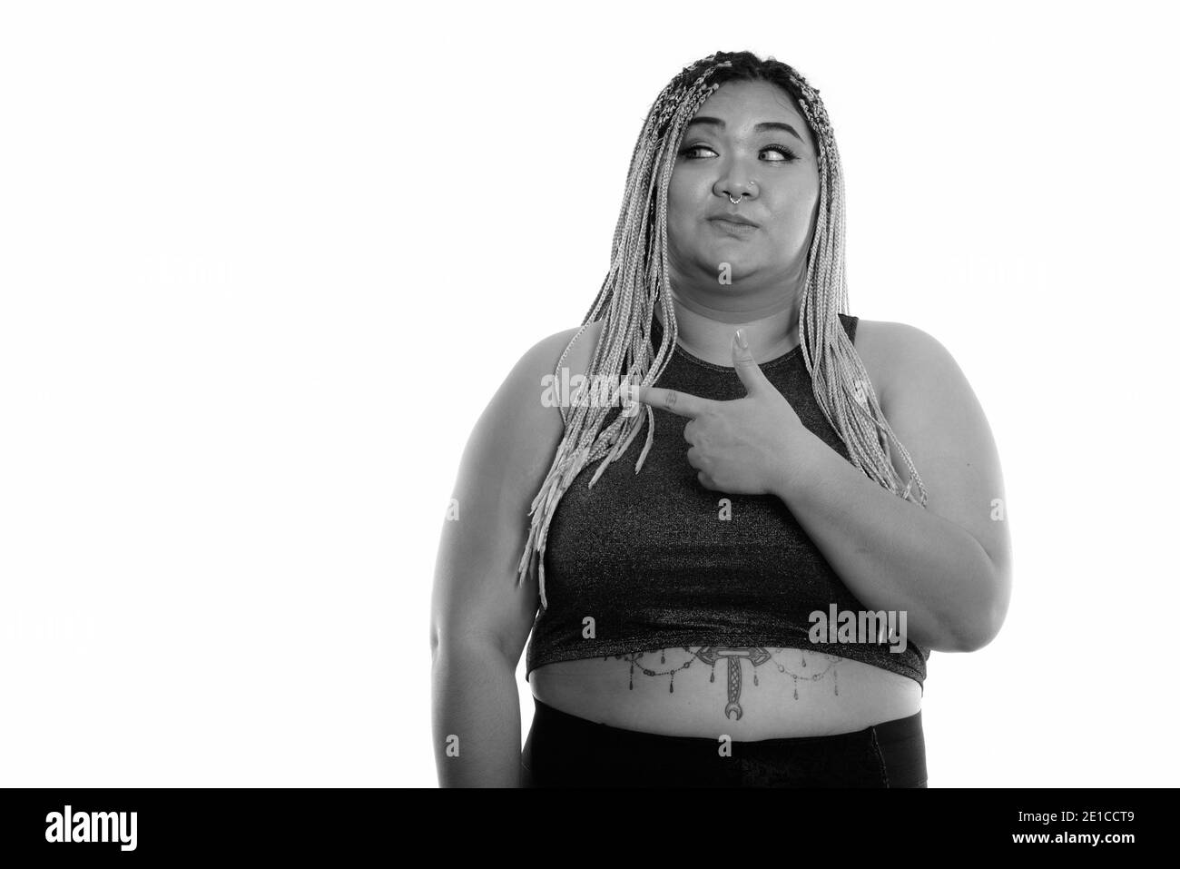 Studio shot of young Asian woman looking fat et montre de l'index sur le côté Banque D'Images