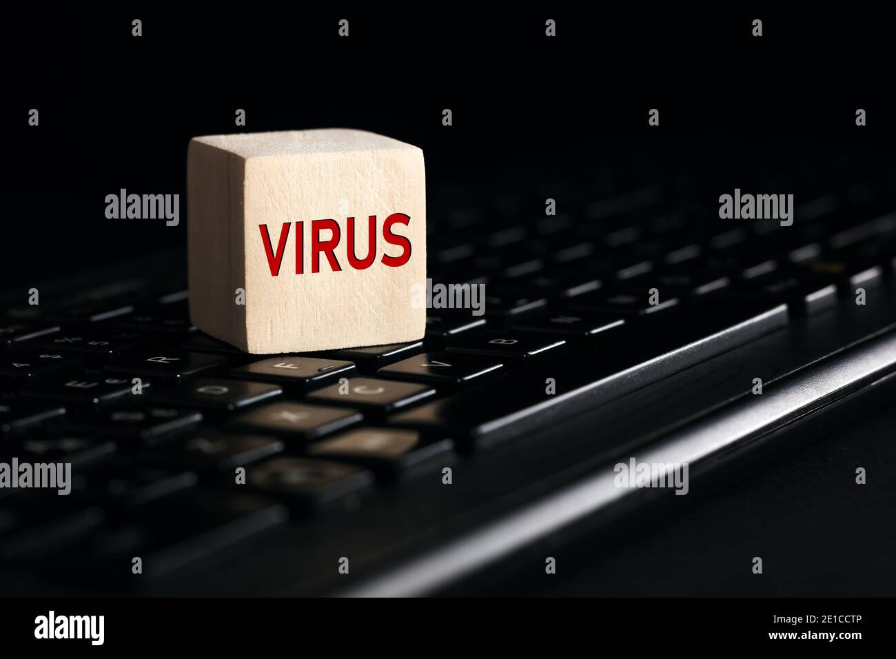 Le mot virus sur bloc de bois avec clavier d'ordinateur sur fond noir. Concept de menace de virus informatique. Banque D'Images