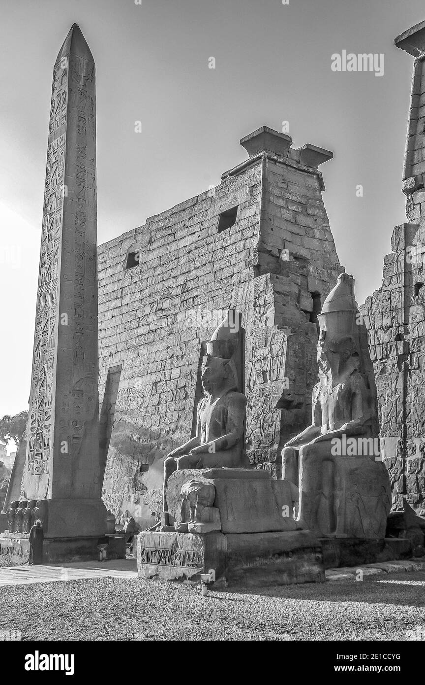 Louxor. C'est l'entrée du temple de Louxor, classé au patrimoine mondial de l'UNESCO depuis 3500 ans, qui fait partie du plus grand complexe de temples du monde, situé sur le Nil à la ville de Louxor, autrefois connue dans le monde antique sous le nom de Thèbes, Construction dont est largement crédité au Pharaon Roi Ramsès II, Ramsès le Grand vu ici assis de chaque côté de la grande entrée pylônes et la colonne obélisque gardien l'entrée du temple Banque D'Images