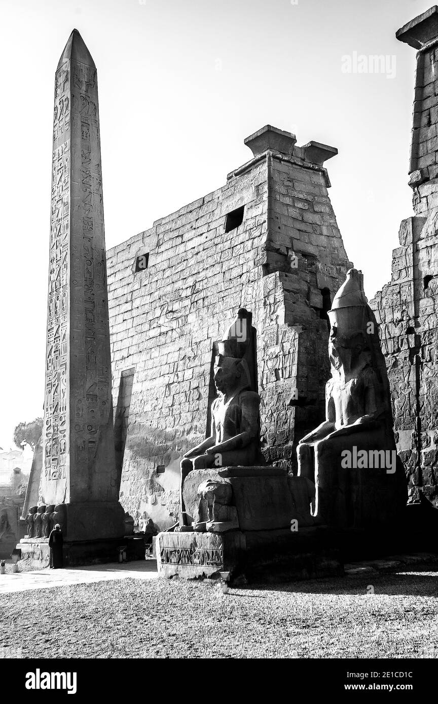 Louxor. C'est l'entrée du temple de Louxor, classé au patrimoine mondial de l'UNESCO depuis 3500 ans, qui fait partie du plus grand complexe de temples du monde, situé sur le Nil à la ville de Louxor, autrefois connue dans le monde antique sous le nom de Thèbes, Construction dont est largement crédité au Pharaon Roi Ramsès II, Ramsès le Grand vu ici assis de chaque côté de la grande entrée pylônes et la colonne obélisque gardien l'entrée du temple Banque D'Images