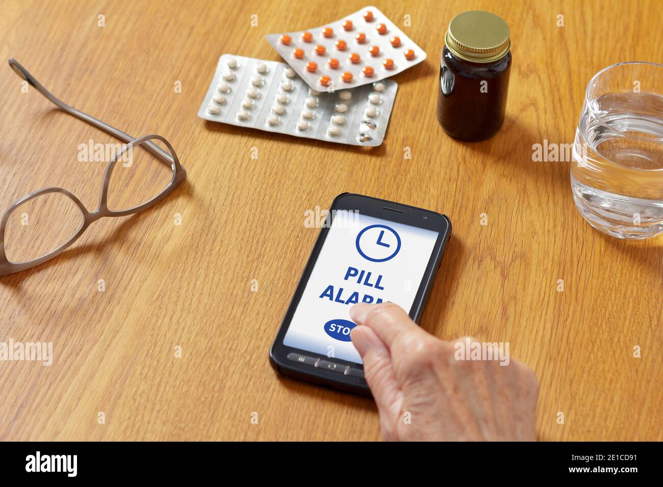 Application d'alarme de pilule sur mobile, cellulaire ou smartphone, avec  verre d'eau, lunettes, médicaments et la main d'une femme âgée Photo Stock  - Alamy