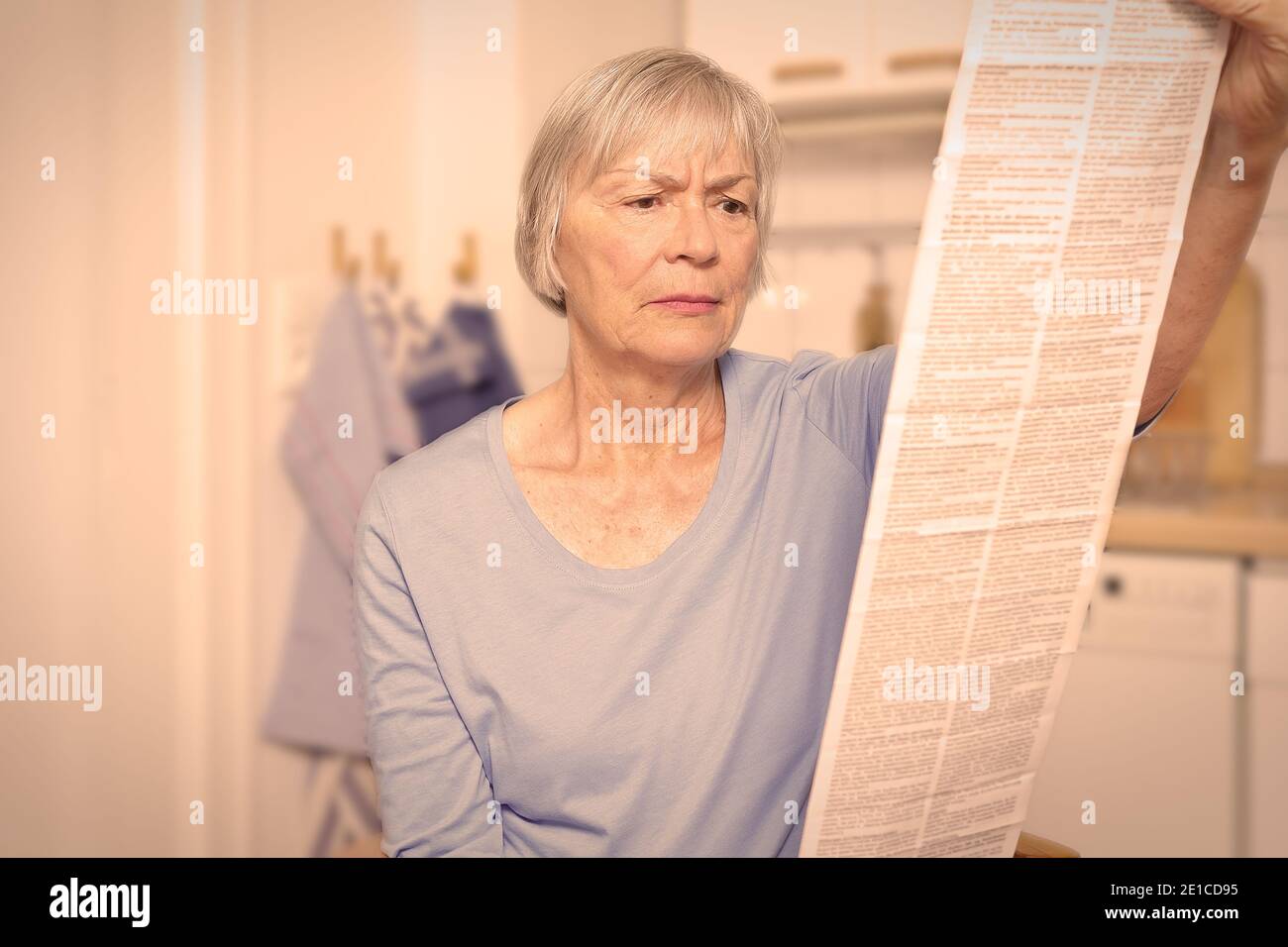 Femme âgée réfléchie avec une très longue notice de médicament pour son médicament prescrit, effet filtre. Banque D'Images