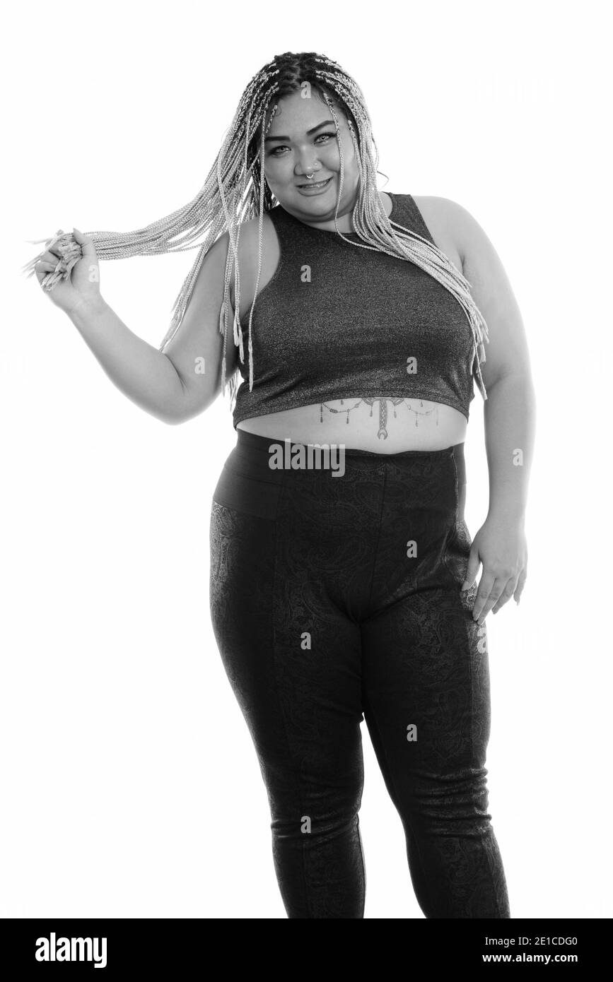 Studio shot of young woman smiling Asian fat heureux en étant debout et jouant avec ses cheveux Banque D'Images Studio shot of young woman smiling Asian fat heureux en étant debout et jouant avec ses cheveux Banque D'Images