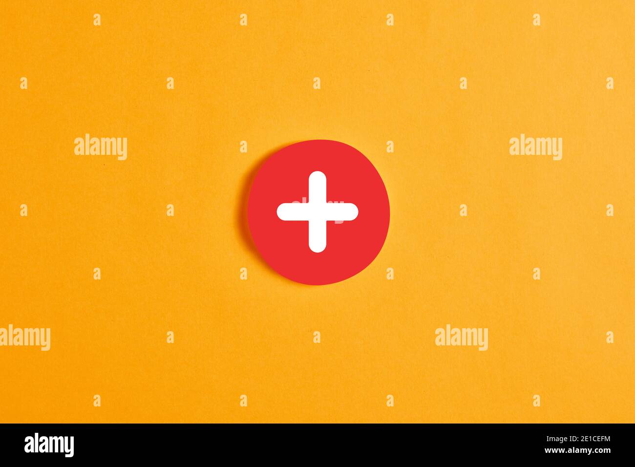 Cercle rond rouge avec un bouton ou une icône plus sur fond jaune. Banque D'Images