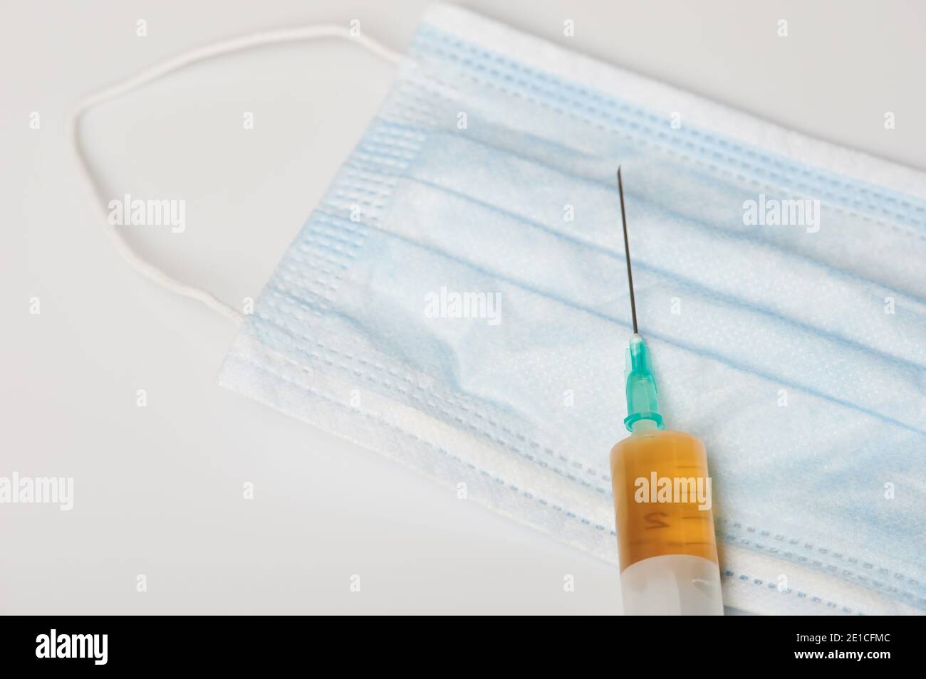 Thème du temps de vaccination. Seringue avec masque de coton sur fond blanc Banque D'Images