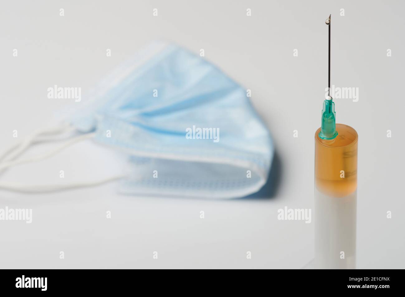 Thème du vaccin contre le virus. Seringue avec médicament sur fond de masque facial Banque D'Images