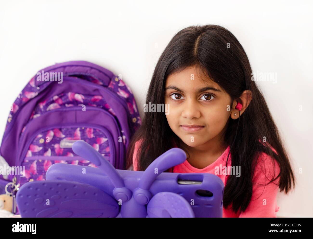 Une petite fille avec des écouteurs et une tablette prenant des cours en ligne pendant une pandémie de covid. concept d'apprentissage en ligne. Banque D'Images