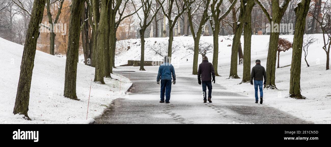 Detroit, Michigan - pendant la pandémie, trois personnes font une promenade tôt le matin à distance sociale dans le cimetière d'Elmwood. Banque D'Images