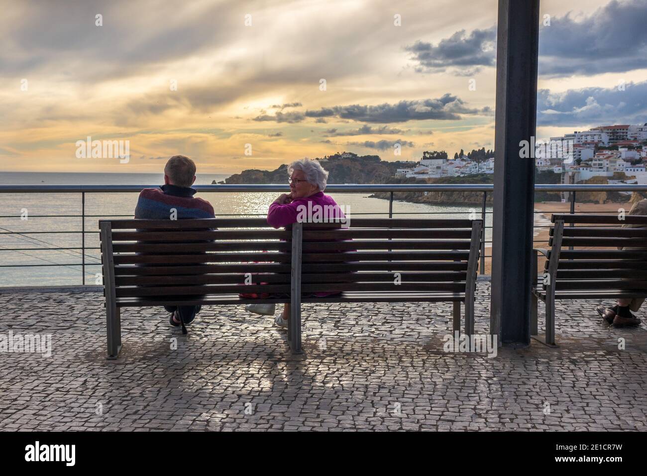 Un couple s'assoit pour profiter du coucher de soleil d'hiver Albufeira Algarve Portugal Banque D'Images