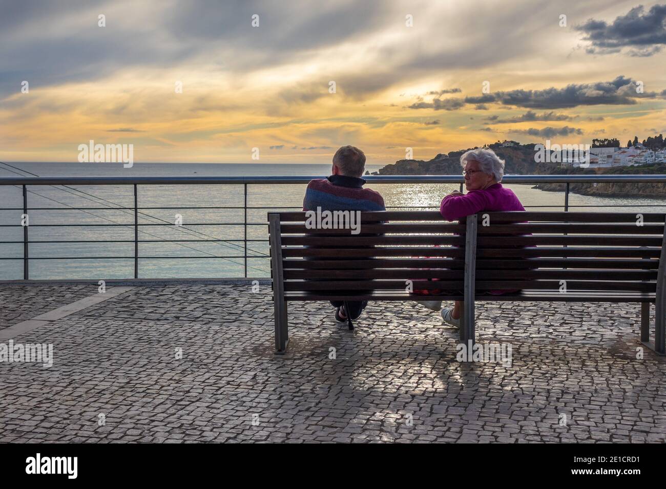 Un couple s'assoit pour profiter du coucher de soleil d'hiver Albufeira Algarve Portugal Banque D'Images