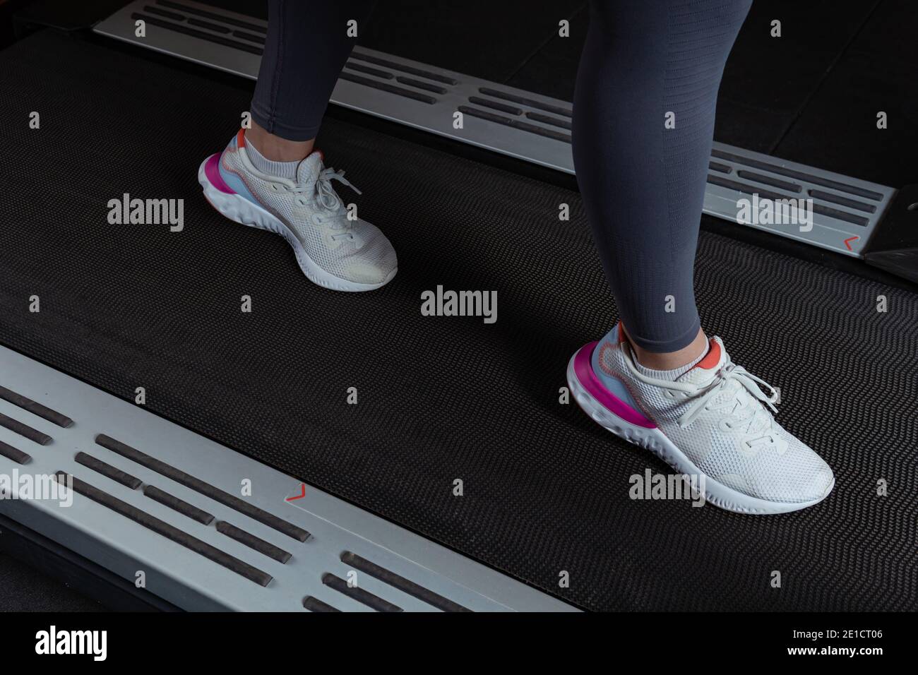 Une fille de forme physique qui s'exécute sur un tapis roulant. Femme avec des jambes musculaires en salle de gym Jeune belle femme sur le tapis roulant dans la salle de gym. Des chaussures en gros plan apparaissent. Banque D'Images