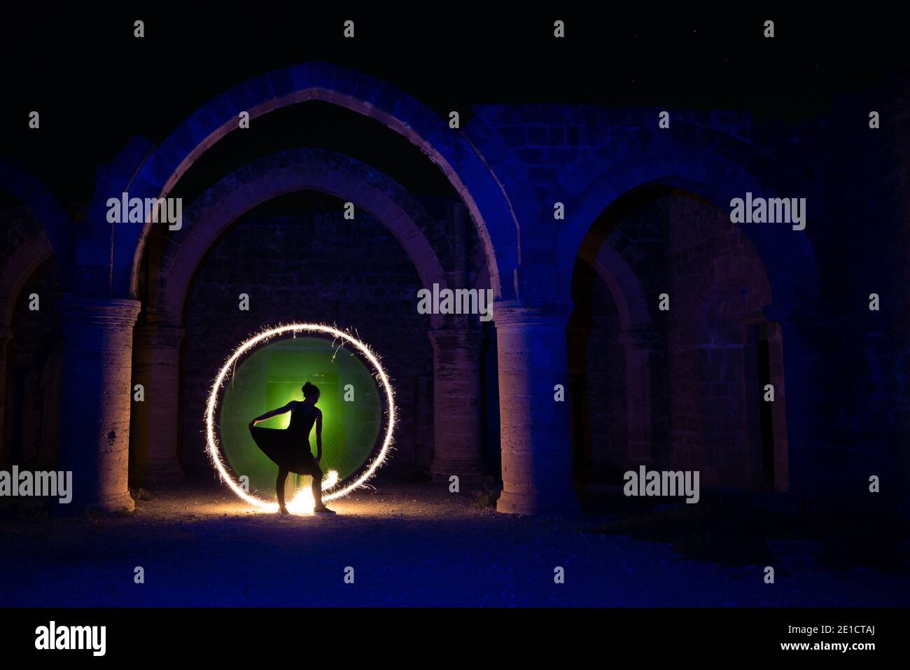 Jeune femme dansant sous une vieille colonne lapidée avec cercle de lumière de peinture derrière. Photographie de peinture légère Banque D'Images