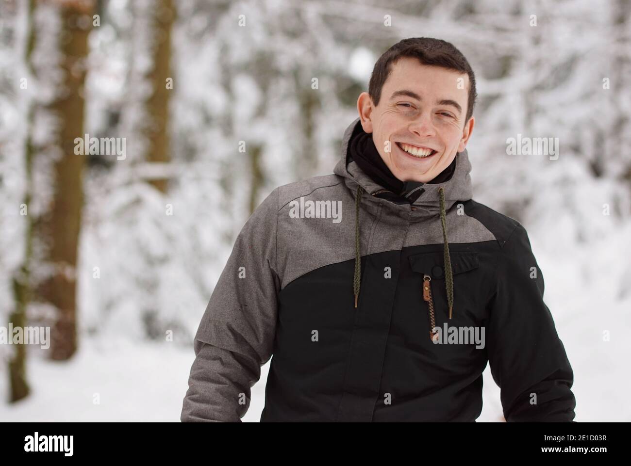 Hiver - un jeune homme heureux s'amusant dans la neige et riant, souriant dans l'appareil photo Banque D'Images