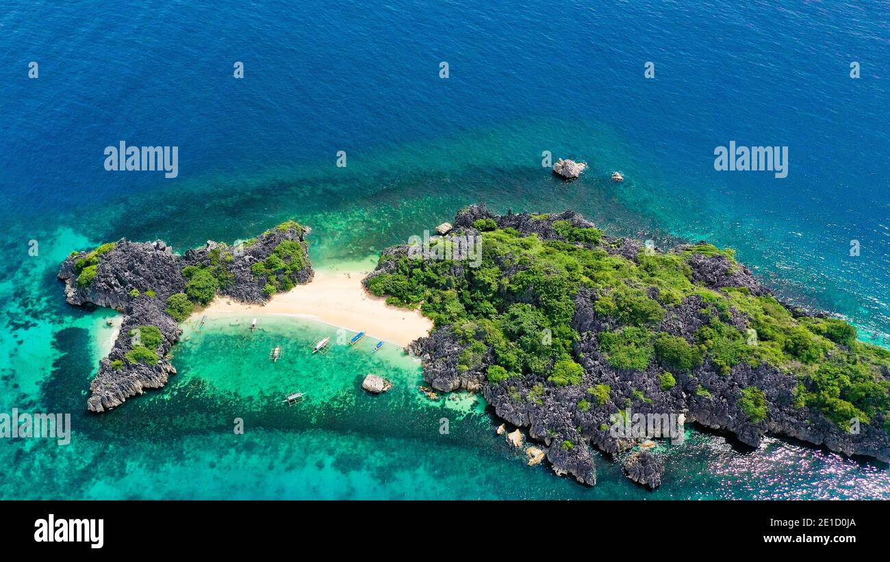 Vue aérienne d'une petite île tropicale isolée avec plage de sable blanc et eaux transparentes bleues et récifs coralliens. Île De Lahos, Îles Caramoan, Phili Banque D'Images