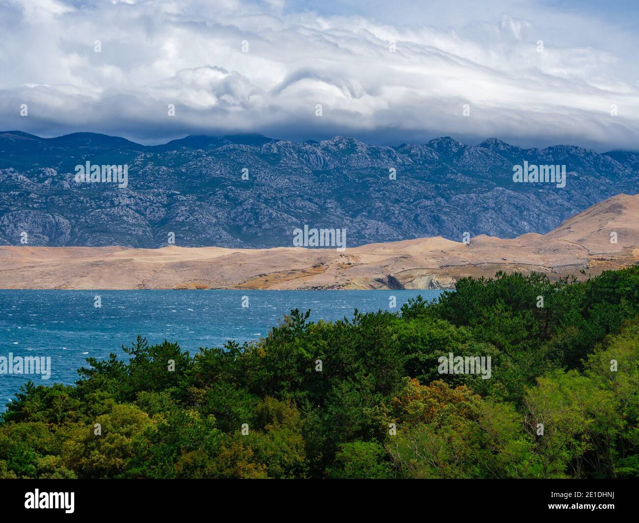 Des nuages en sens inverse. Nuages sur les collines de l'île de Pag en Croatie. Vue de dessus de la baie entourée de montagnes et de verdure. Banque D'Images
