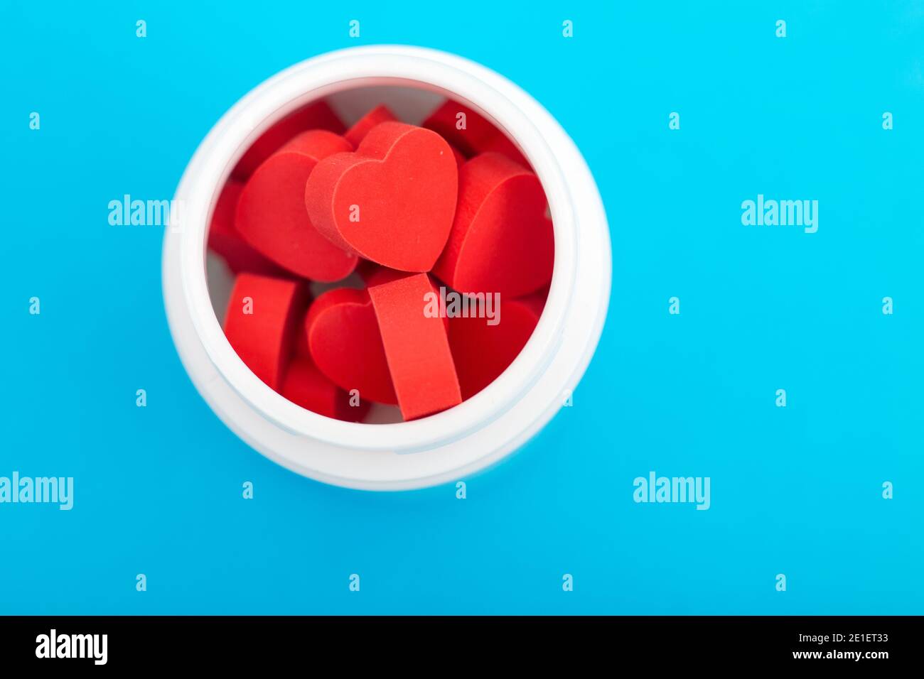 Pilules en forme de coeur rouge avec bouteille en plastique sur fond bleu.concept amour addiction, drogues d'amour, Saint-Valentin et dépression Banque D'Images