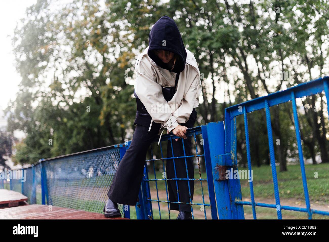 La femme monte la clôture dans un capot Banque D'Images