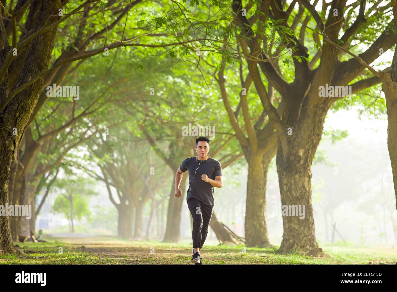 un jeune homme qui fait du jogging dans le parc et écoute de la musique sur son téléphone portable Banque D'Images
