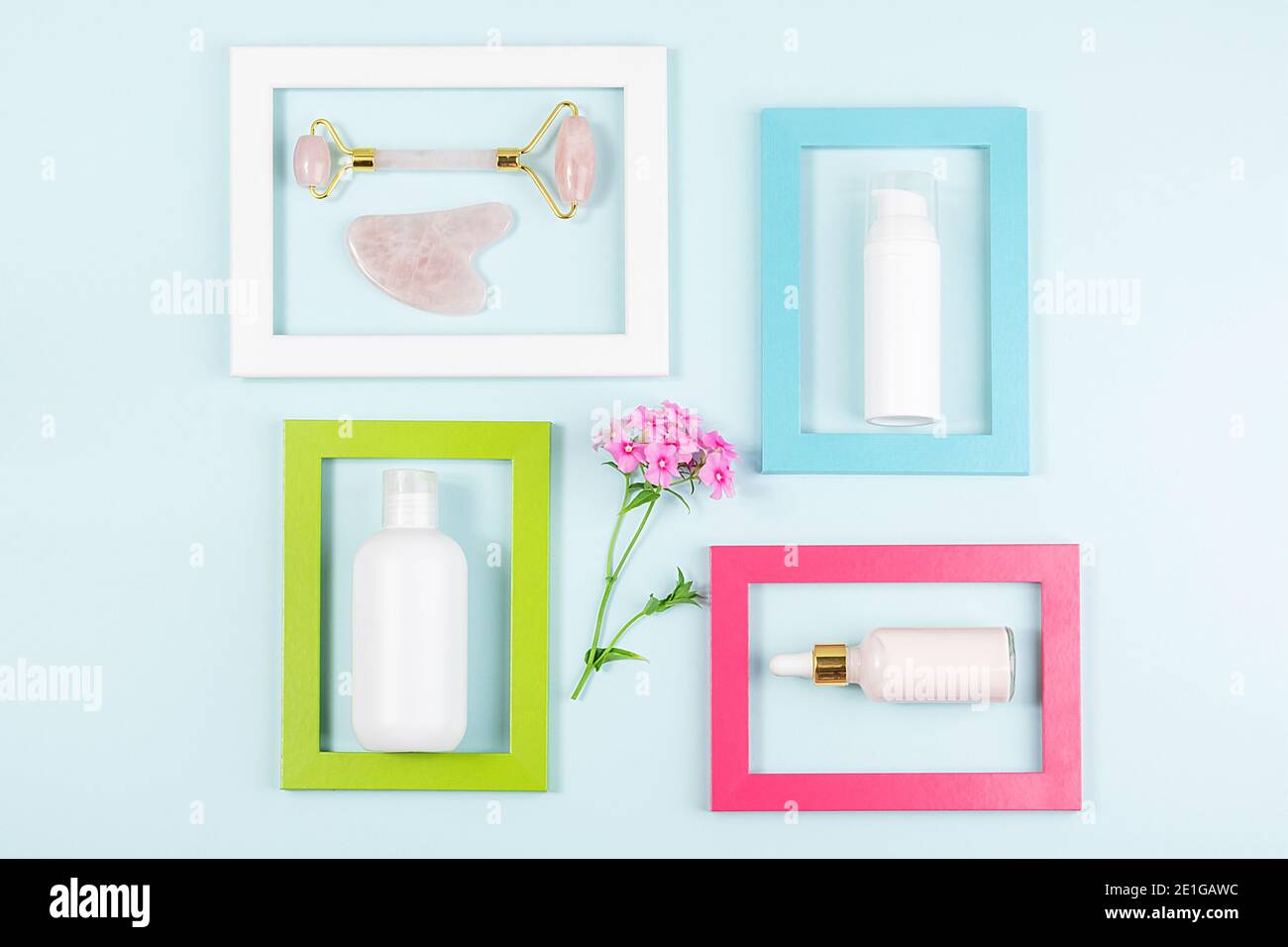 Cosmétiques pour le soin de la peau visage, rouleau de quartz rose cristal et outil de massage Gua sha dans des cadres lumineux sur fond bleu. Beauté cosmétique créative Banque D'Images