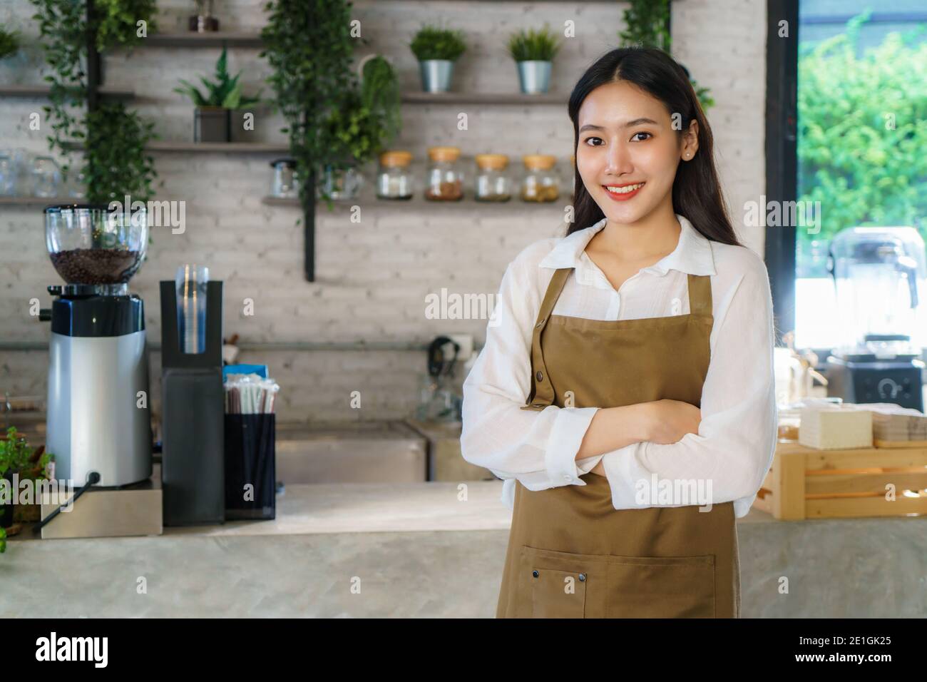 Homme asiatique Barista ou propriétaire petite entreprise dans la recherche de tablier à l'appareil photo et bras croisés au café moderne Banque D'Images
