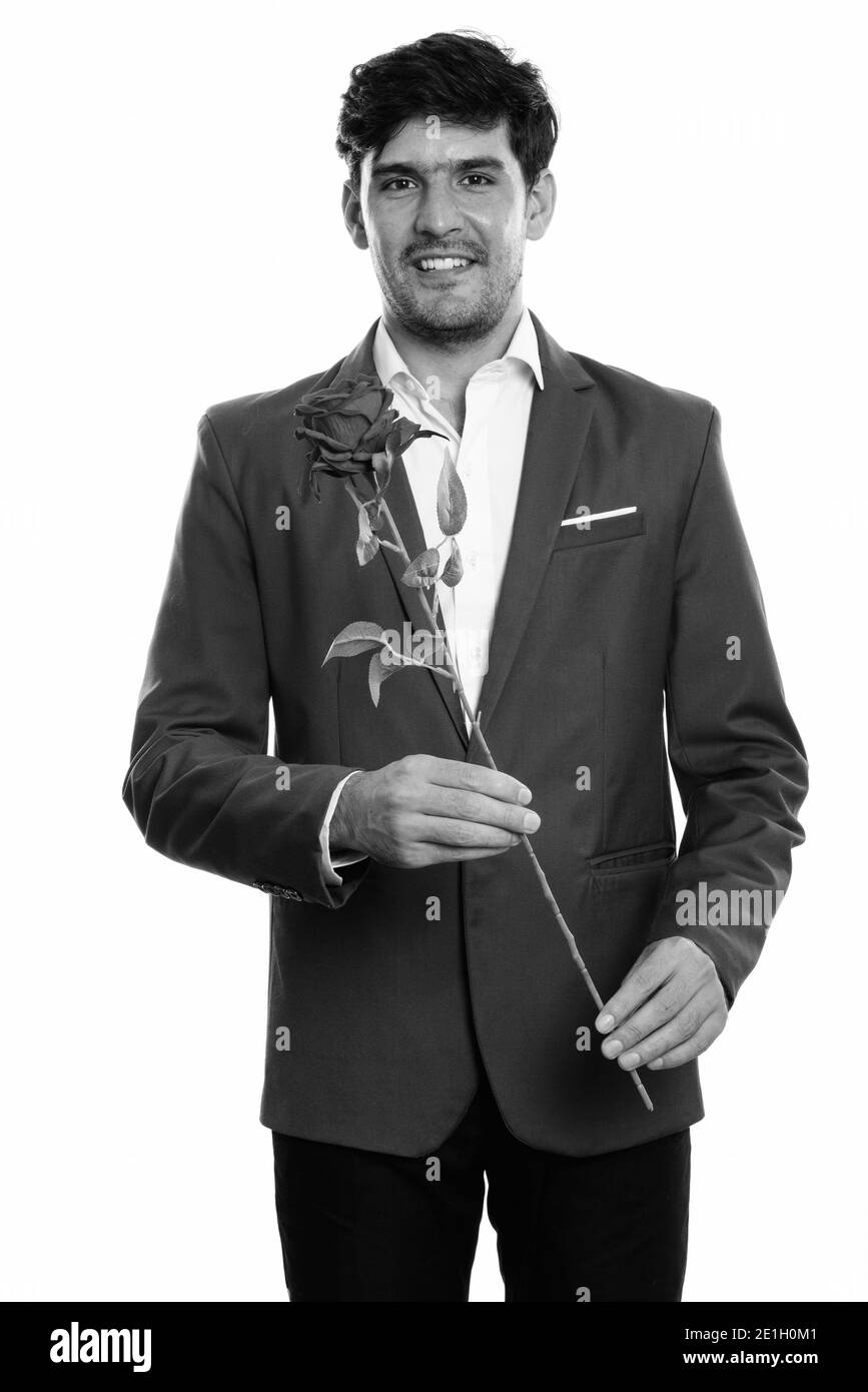 Studio shot of young businessman smiling persan heureux tout en maintenant rose rouge Banque D'Images