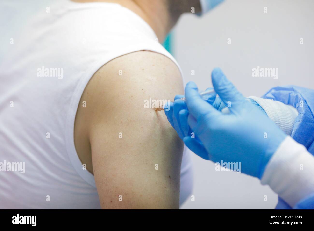 Détails sur un homme qui reçoit une injection intramusculaire avec le vaccin contre le SRAS-COV-2 dans un hôpital par un travailleur médical. Banque D'Images