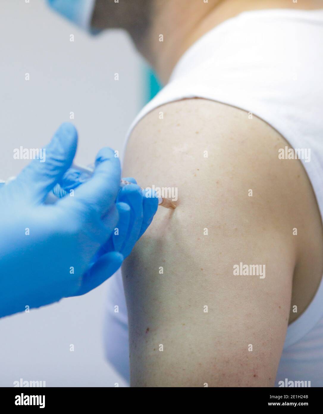 Détails sur un homme qui reçoit une injection intramusculaire avec le vaccin contre le SRAS-COV-2 dans un hôpital par un travailleur médical. Banque D'Images