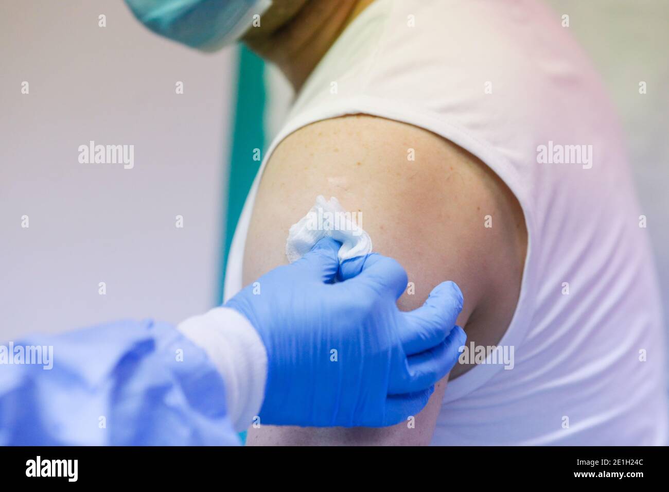 Détails sur un homme qui reçoit une injection intramusculaire avec le vaccin contre le SRAS-COV-2 dans un hôpital par un travailleur médical. Banque D'Images